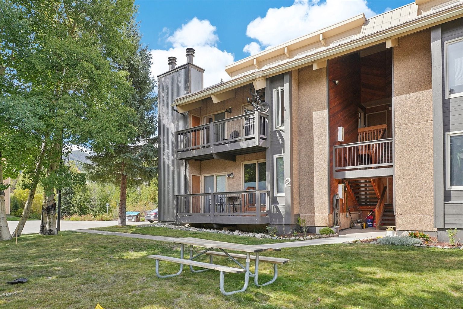 Exterior of 601 Galena Unit C, two-story condo with aspens, balconies, decks, and chimney detail